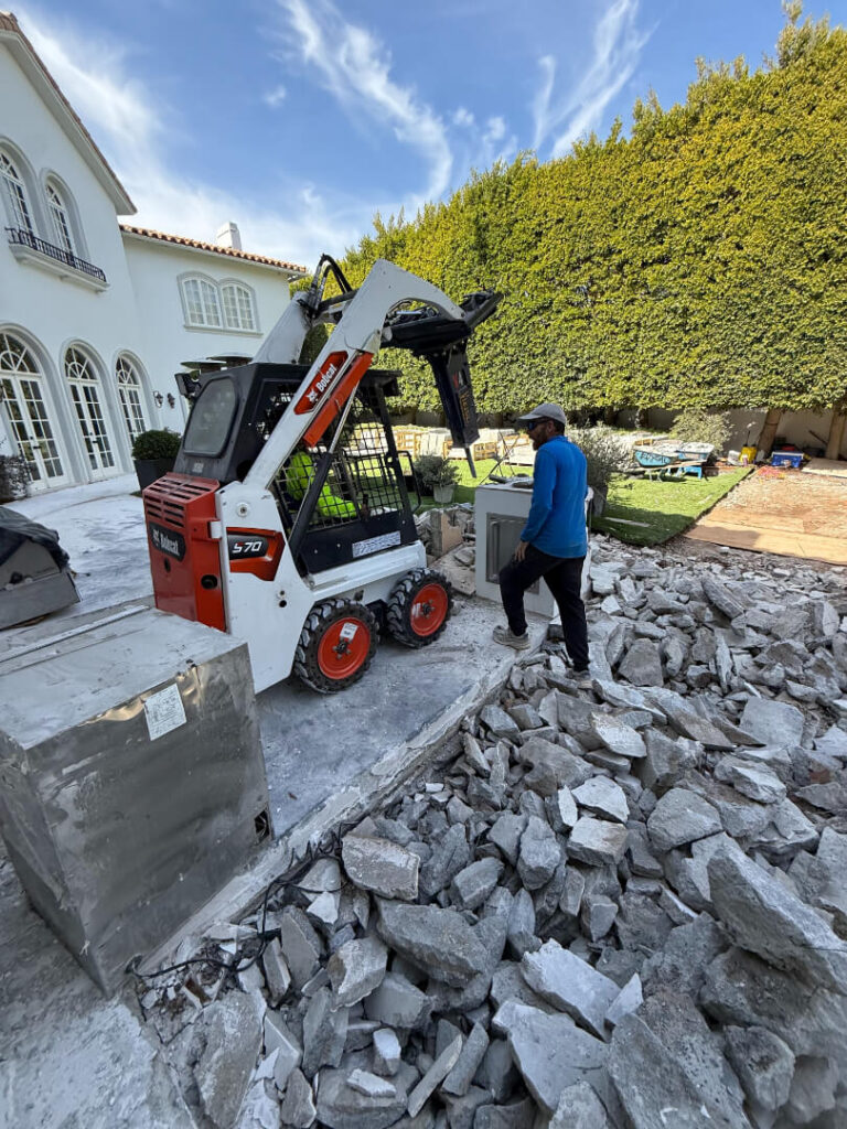 A construction worker operates a Bobcat S70 skid-steer loader on a residential site.