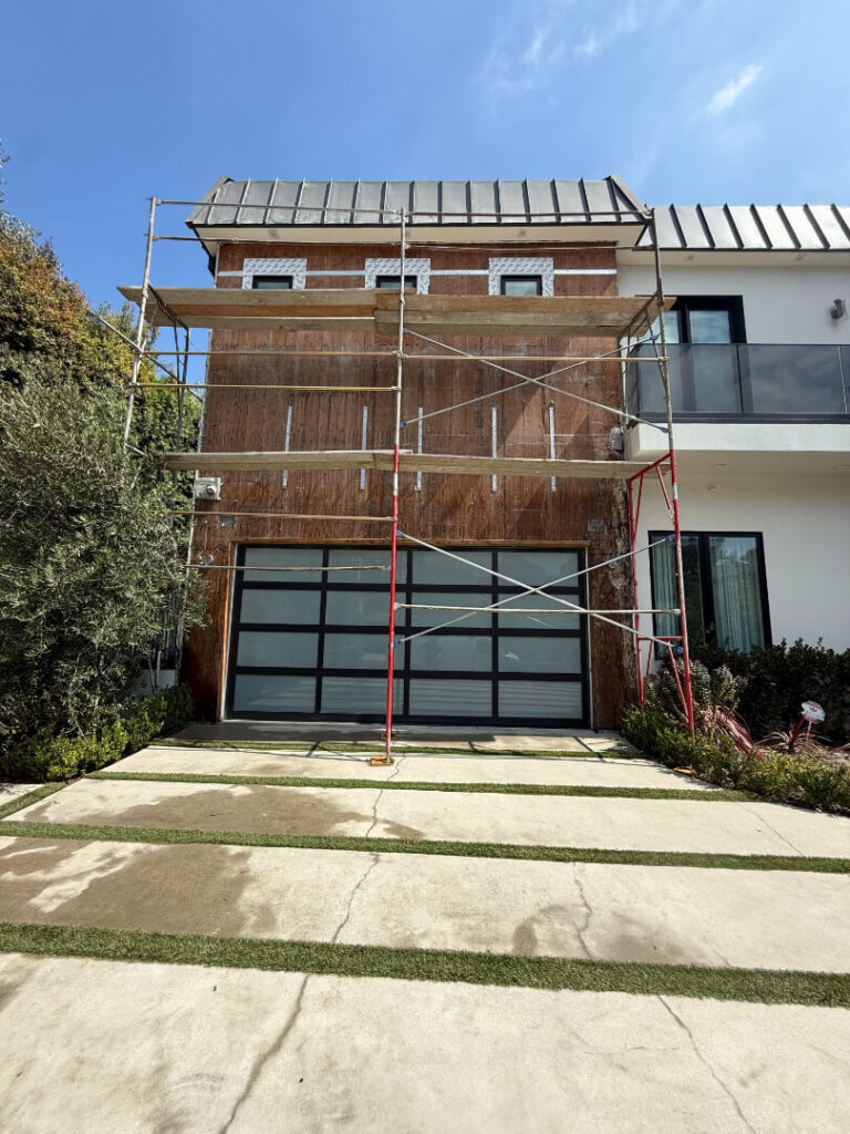 Scaffolding surrounds the front of a house undergoing exterior renovations.