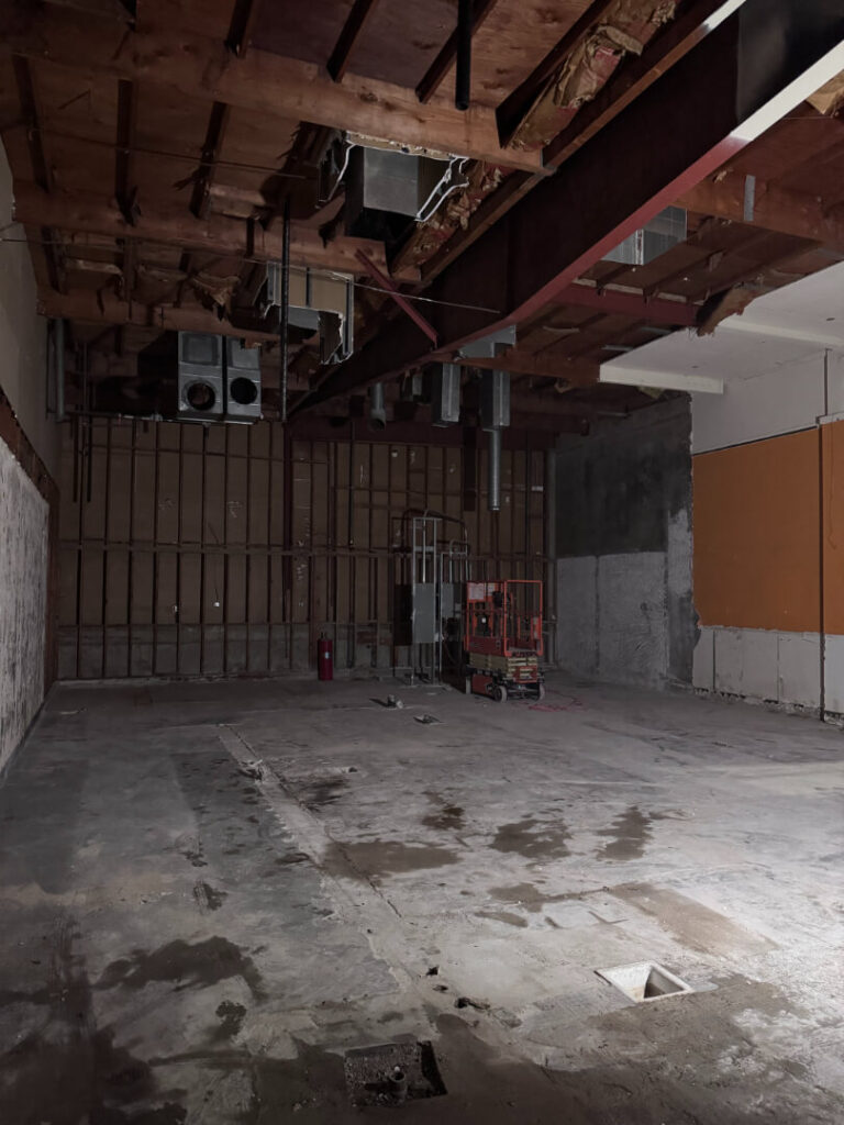 Empty, partially constructed interior space with exposed beams and ductwork.